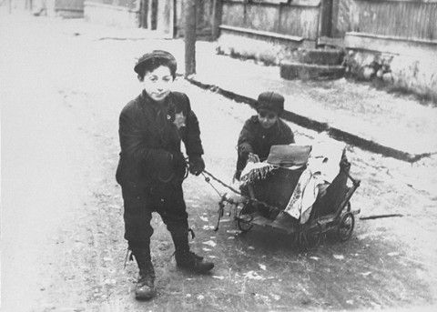 Two young boys pull and push a wagon in the Kovno ghetto